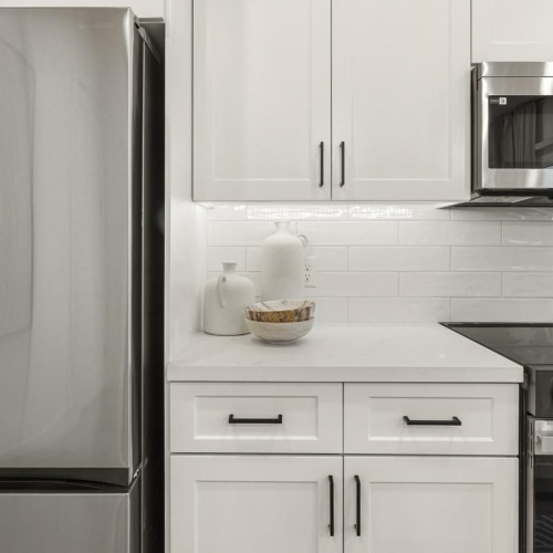 a kitchen with white cabinets a fridge and a stovetop