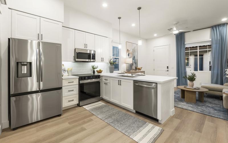 a kitchen with white cabinets a fridge a stovetop and a dishwasher