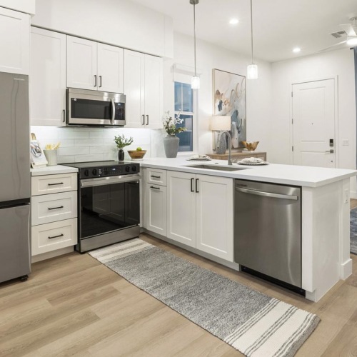 a kitchen with white cabinets a fridge a stovetop and a dishwasher